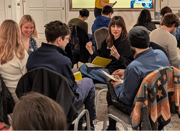 Photograph of researchers sitting in small discussion groups.