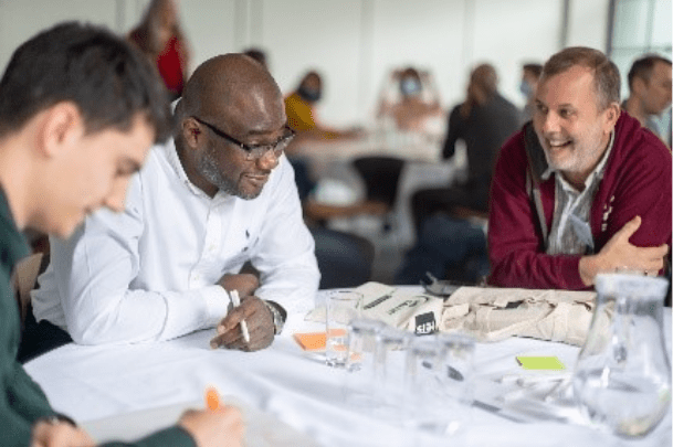 Three people seated at workshop table
